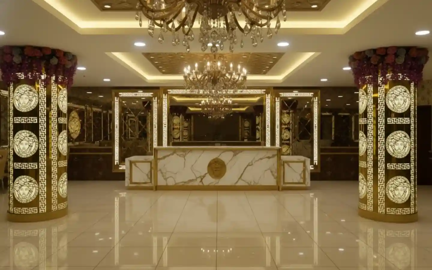 Luxury banquet hall reception area featuring a marble counter, gold-accented pillars with Medusa motifs, and crystal chandeliers