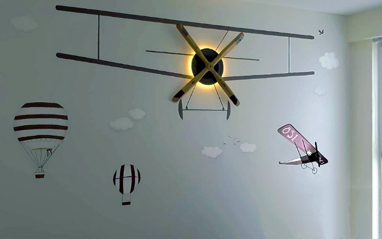 Kids bedroom wall featuring aviation-themed decor with a 3D airplane propeller light, hot air balloon decals, and vintage biplane murals