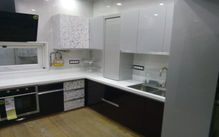 Contemporary home kitchen featuring a combination of high-gloss black and patterned white cabinetry with clean white countertops and a stainless steel sink