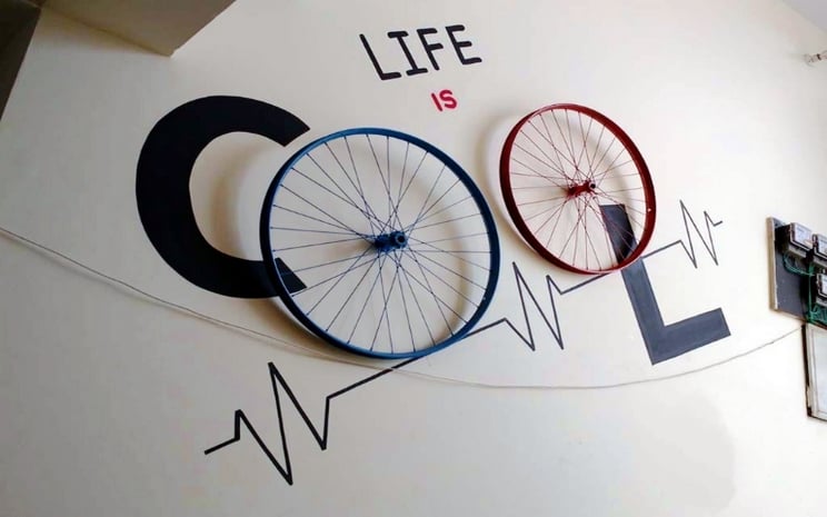Creative interior wall design with bicycle wheels forming the word cool and life is cool quote decor