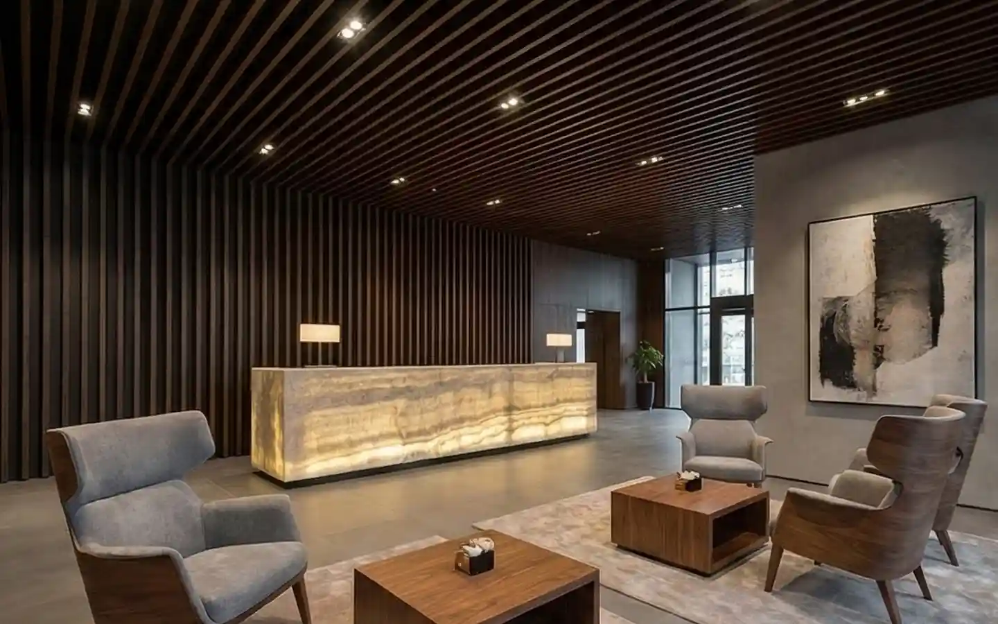 Modern hotel lobby reception featuring a backlit onyx stone desk, dark slat wood wall paneling, and contemporary wingback armchairs