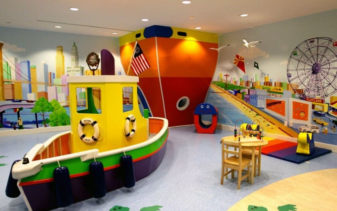 Bright indoor children’s playroom with boat-shaped play structure, colorful sections, bead maze toys, and harbor mural