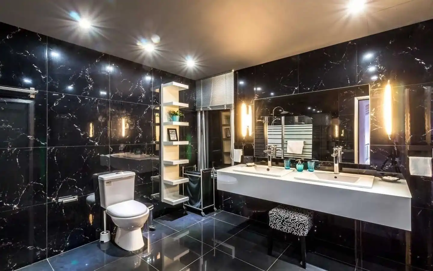 Modern luxury bathroom interior design in Delhi featuring black marble wall tiles, a double vanity sink, and contemporary lighting