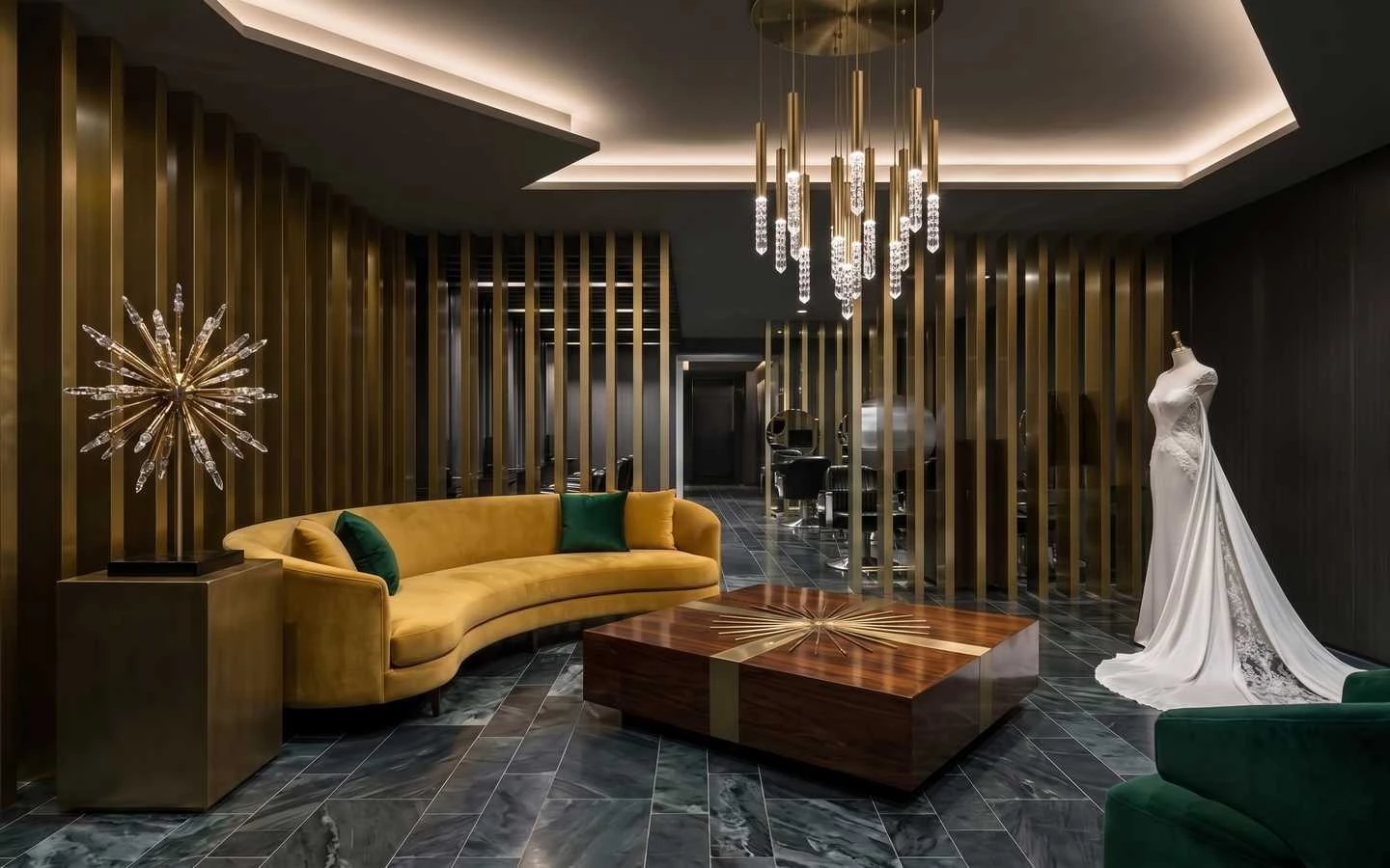 Luxury bridal salon waiting area featuring a curved mustard yellow velvet sofa, dark marble floors, gold vertical slat walls, and a modern chandelier