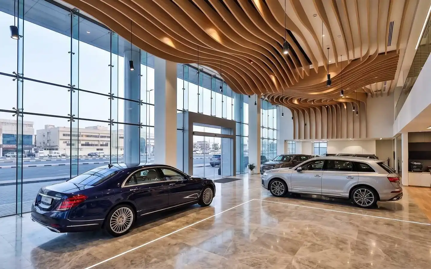 Modern luxury car showroom interior design featuring a parametric wave wood ceiling, floor-to-ceiling glass walls, and polished marble flooring