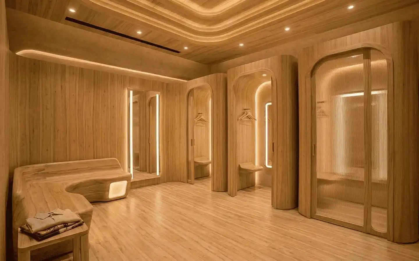 Modern luxury showroom interior featuring arched wooden fitting rooms with ambient cove lighting and minimalist wood textures
