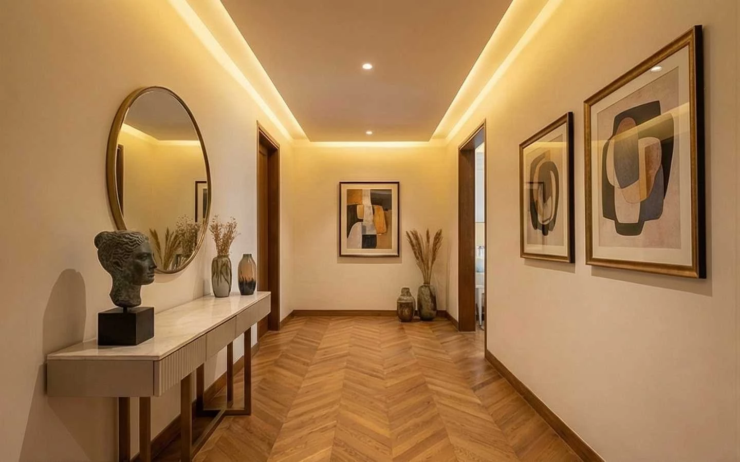 Luxury hallway interior design featuring oak chevron wood flooring, a modern white console table with a gold-framed round mirror, and warm recessed cove lighting