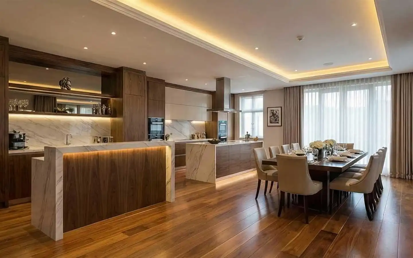 Modern open-concept kitchen and dining area with marble waterfall islands, dark walnut cabinetry, warm cove lighting, and a large formal dining table
