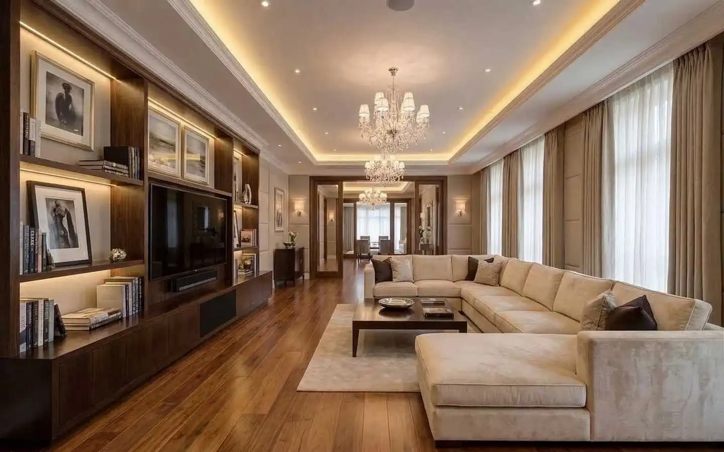 Luxury modern living room featuring a large cream sectional sofa, custom dark wood built-in shelving with integrated lighting, and elegant crystal chandeliers over hardwood floors