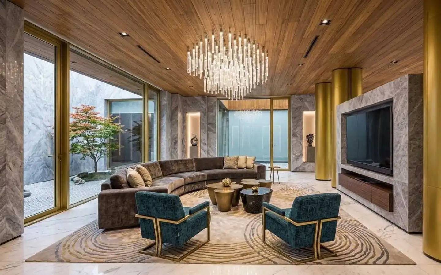 Luxury villa family room featuring a custom marble TV wall, a curved velvet sectional sofa, teal accent chairs, and a glass wall overlooking a private Japanese maple Zen garden
