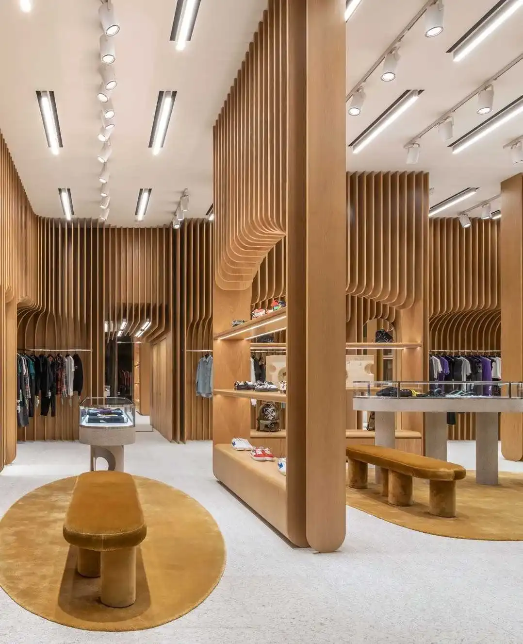 Modern luxury retail store interior featuring dramatic floor-to-ceiling slatted wood partitions, velvet benches, and designer clothing displays