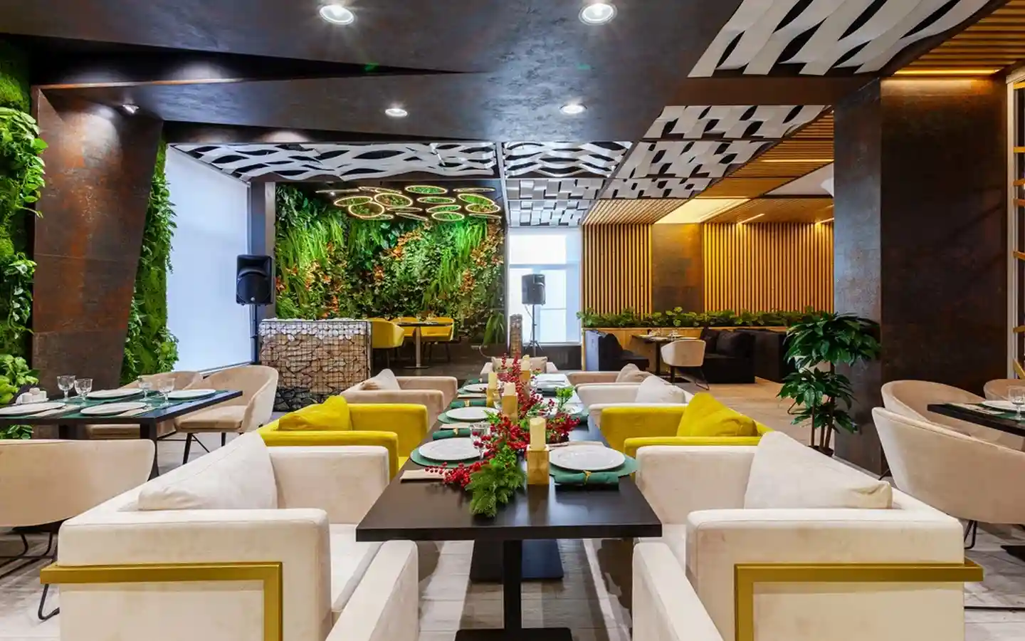 Modern restaurant interior design featuring a vertical garden green wall, geometric ceiling panels, and luxury velvet armchair seating