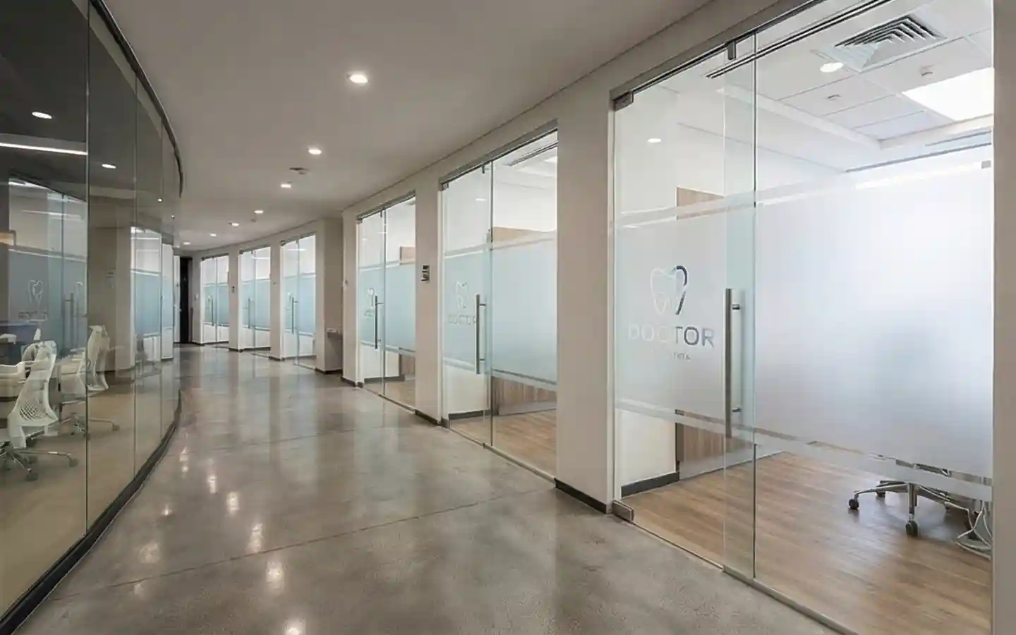 Modern dental clinic interior featuring frameless glass partitions with frosted privacy film and polished concrete floors