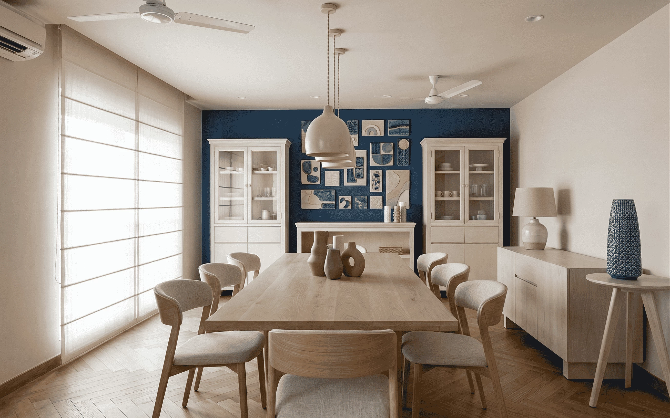 Modern dining room interior design featuring a wooden table, light oak chairs, and a navy blue accent wall with a gallery of abstract art