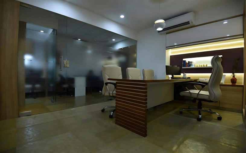 Modern executive office featuring a custom wood-slatted desk, white leather ergonomic chairs, frosted glass partitions, and integrated LED cove lighting