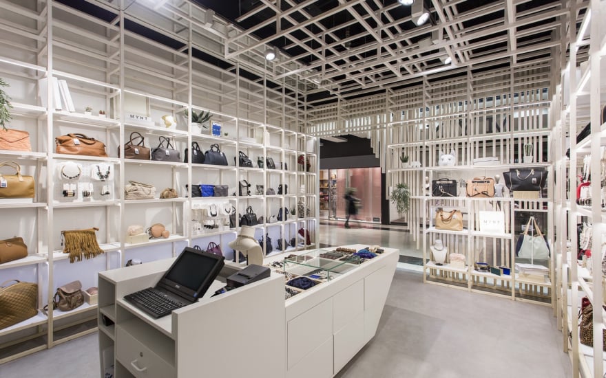 Retail store wall display with handbags, jewelry, and accessories arranged on white shelves