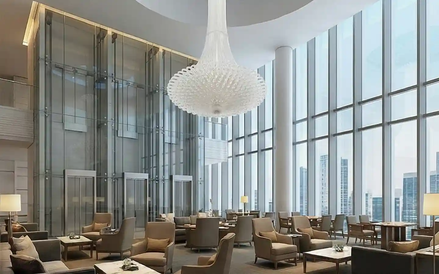 Grand hotel atrium lounge featuring glass elevators, a large statement chandelier, and high-rise city views through floor-to-ceiling windows