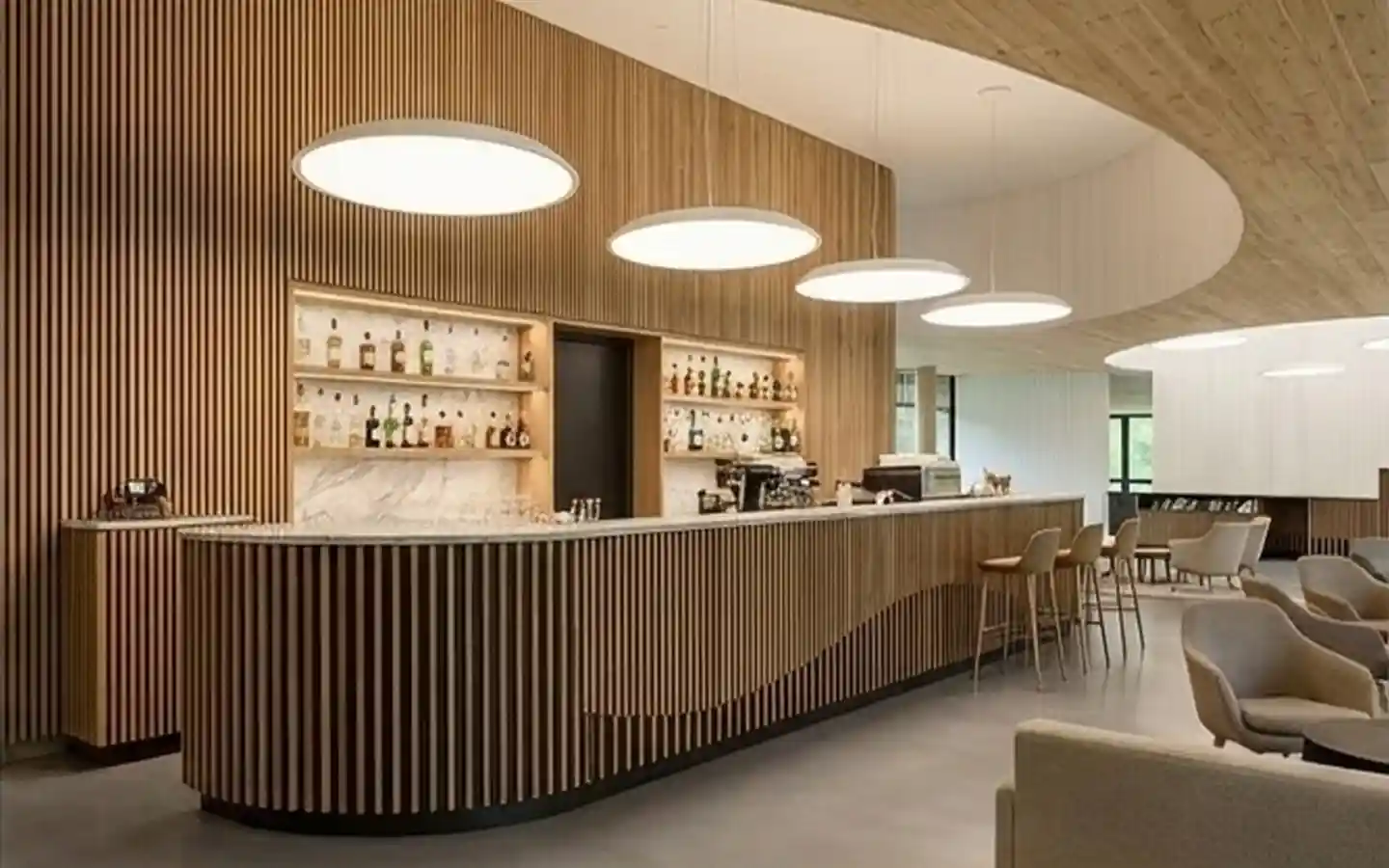 Modern hotel lounge bar featuring vertical wood slat walls, curved marble counter, and circular pendant lighting
