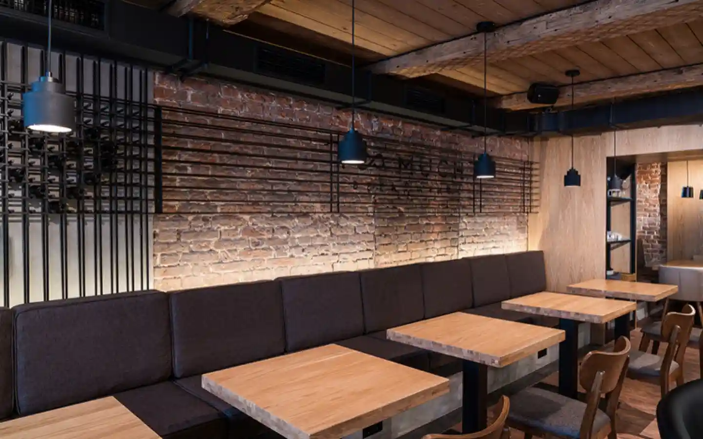 Industrial style restaurant interior featuring exposed brick walls, wooden ceilings, and custom banquet seating