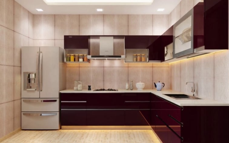 Modern L-shaped modular home kitchen featuring high-gloss maroon cabinetry, warm under-cabinet LED lighting, a white countertop, and a stainless steel refrigerator