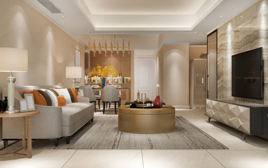 Stylish modern living and dining area with beige sofa, orange cushions, gold coffee table, chandelier, and marble TV wall