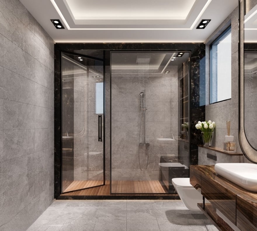 Luxury modern bathroom design featuring grey stone wall tiles, a walk-in glass shower with a wood-slat floor, a dark marble-framed shower entryway, and a floating wood vanity with a vessel sink
