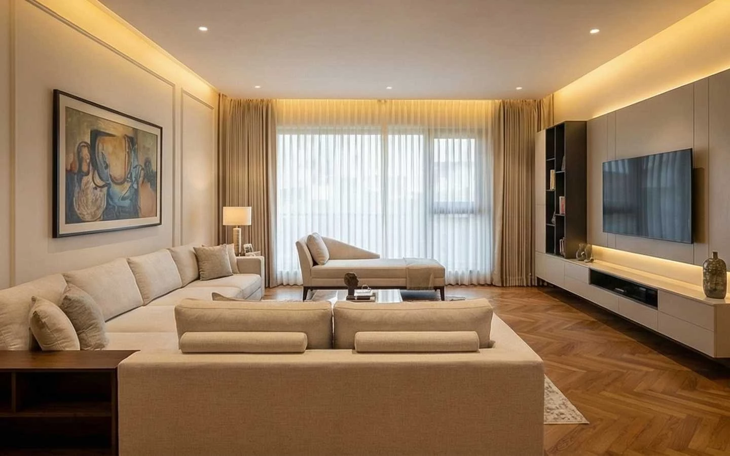 Modern luxury living room interior featuring a large cream sectional sofa, a minimalist wall-mounted TV unit with integrated lighting, sheer floor-to-ceiling curtains, and oak chevron wood flooring