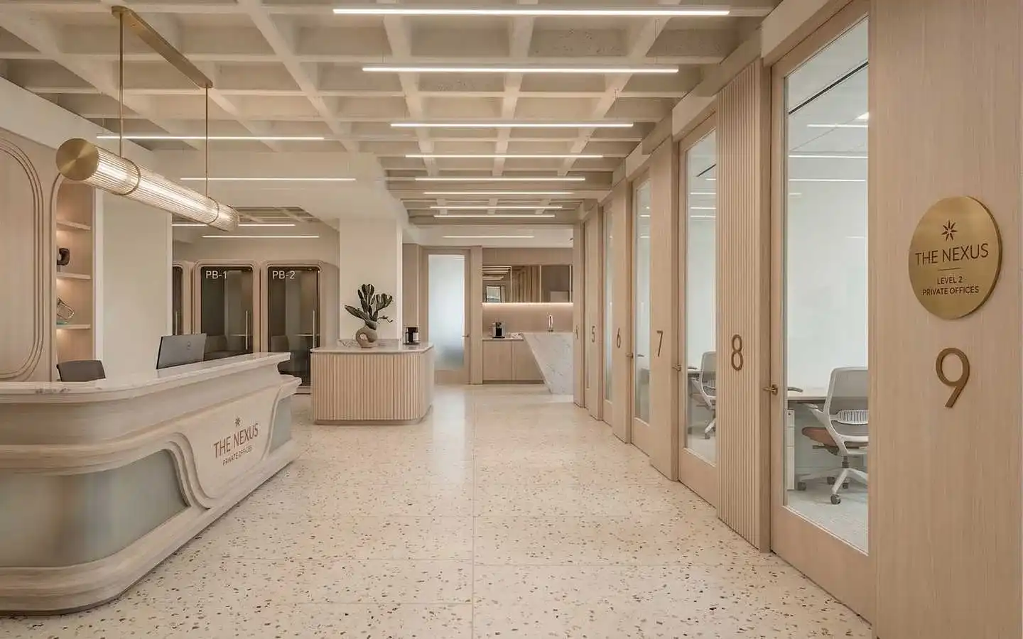 Modern luxury office reception area at The Nexus featuring a curved marble desk, glass private office suites, coffered ceilings, and minimalist neutral interior design