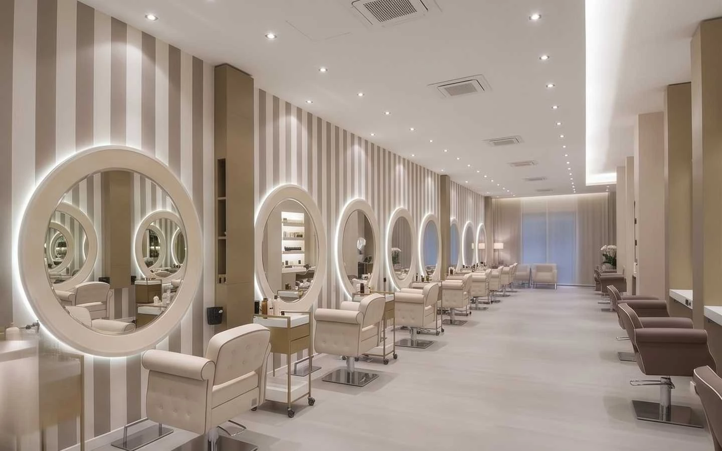 Modern luxury hair salon interior featuring circular backlit mirrors, cream styling chairs, and striped wallpaper
