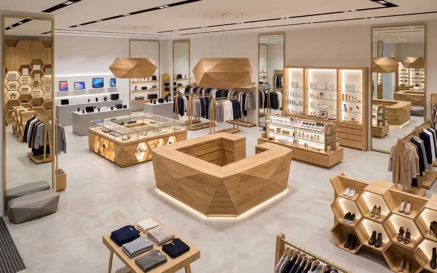 Modern minimalist lifestyle showroom interior featuring geometric wood display counters, honeycomb shoe shelving, custom apparel racks, and a sleek electronics display area