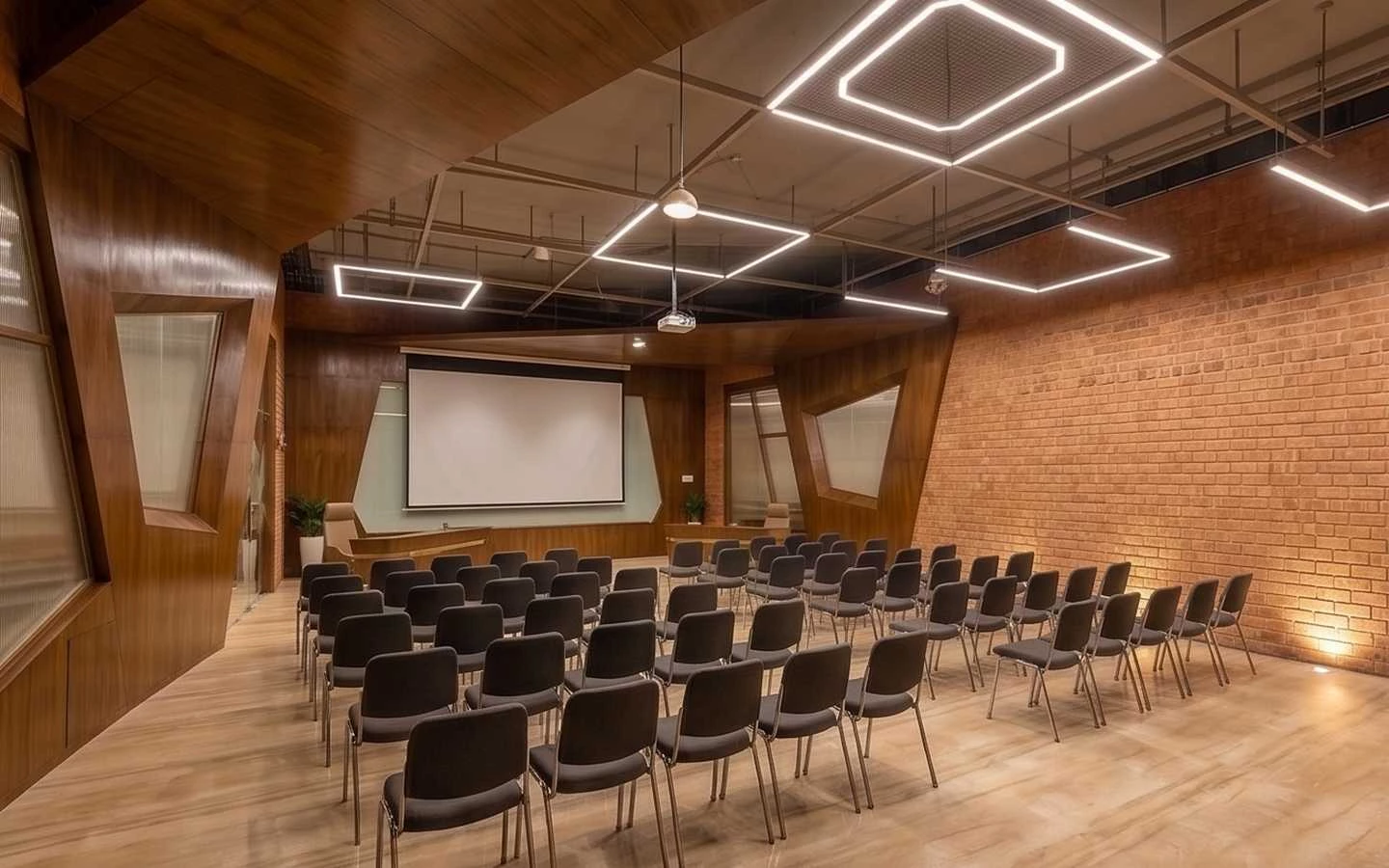 Modern office conference hall interior featuring wooden wall paneling, exposed brick walls, and geometric LED ceiling lighting