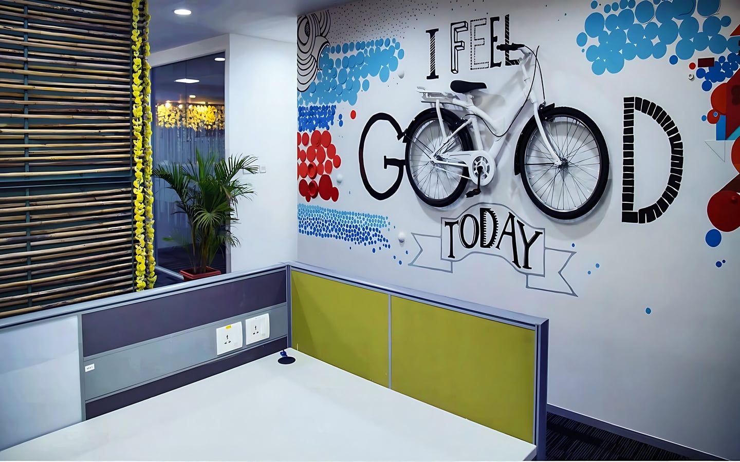 Creative modern office interior design featuring a white bicycle mounted on a wall with 'I Feel Good Today' typography and colorful geometric murals