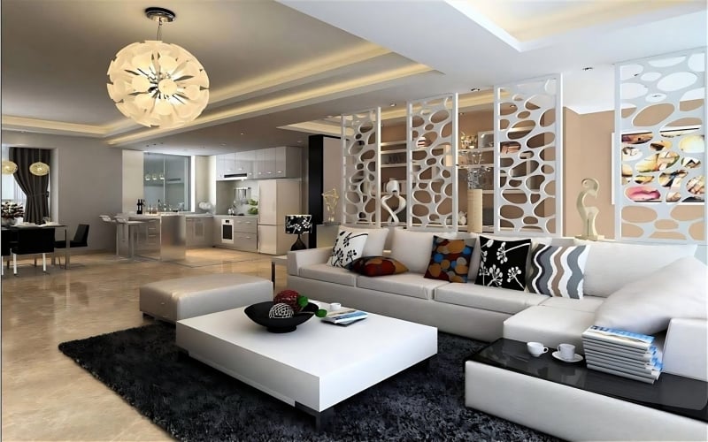 Contemporary open-concept living room with white sectional sofa, colorful pillows, coffee table, and sleek kitchen design
