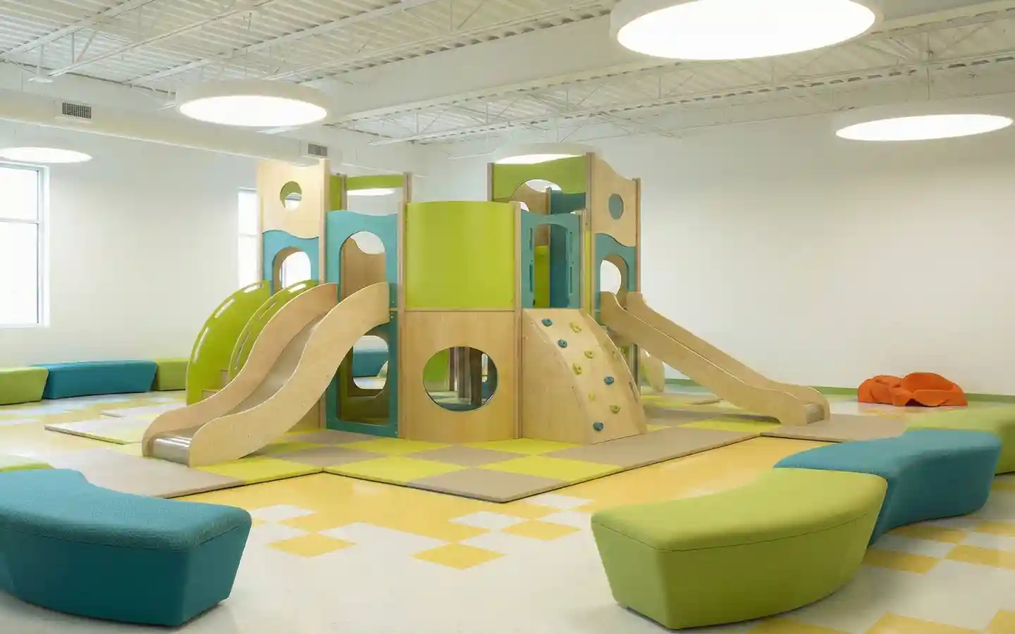 Modern indoor wooden play structure for preschool interior design featuring slides and climbing wall