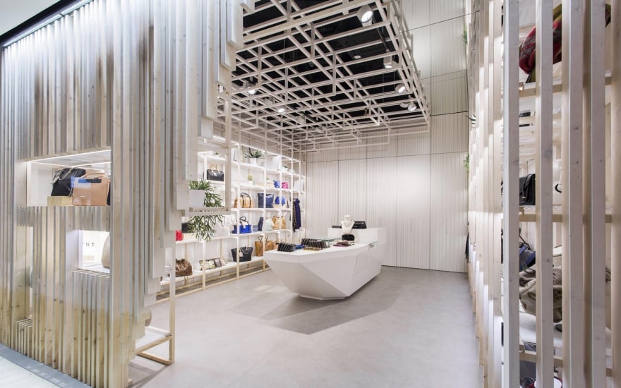 Modern retail store interior with central display counter and handbag shelving in minimalist design