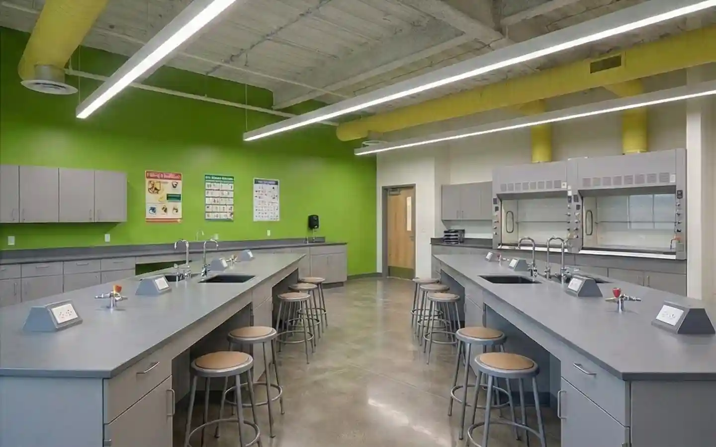Modern school science lab interior with professional workstations, lab sinks, fume hoods, and industrial-style ceiling