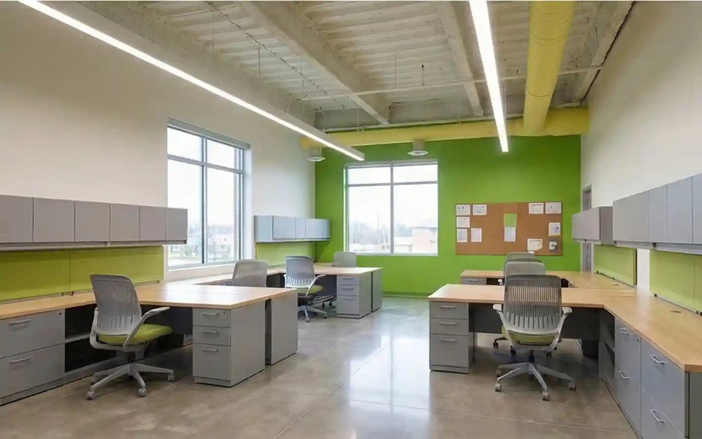Modern school staff office featuring ergonomic workstations, lime green accent walls, industrial exposed ceilings, and ample storage cabinetry