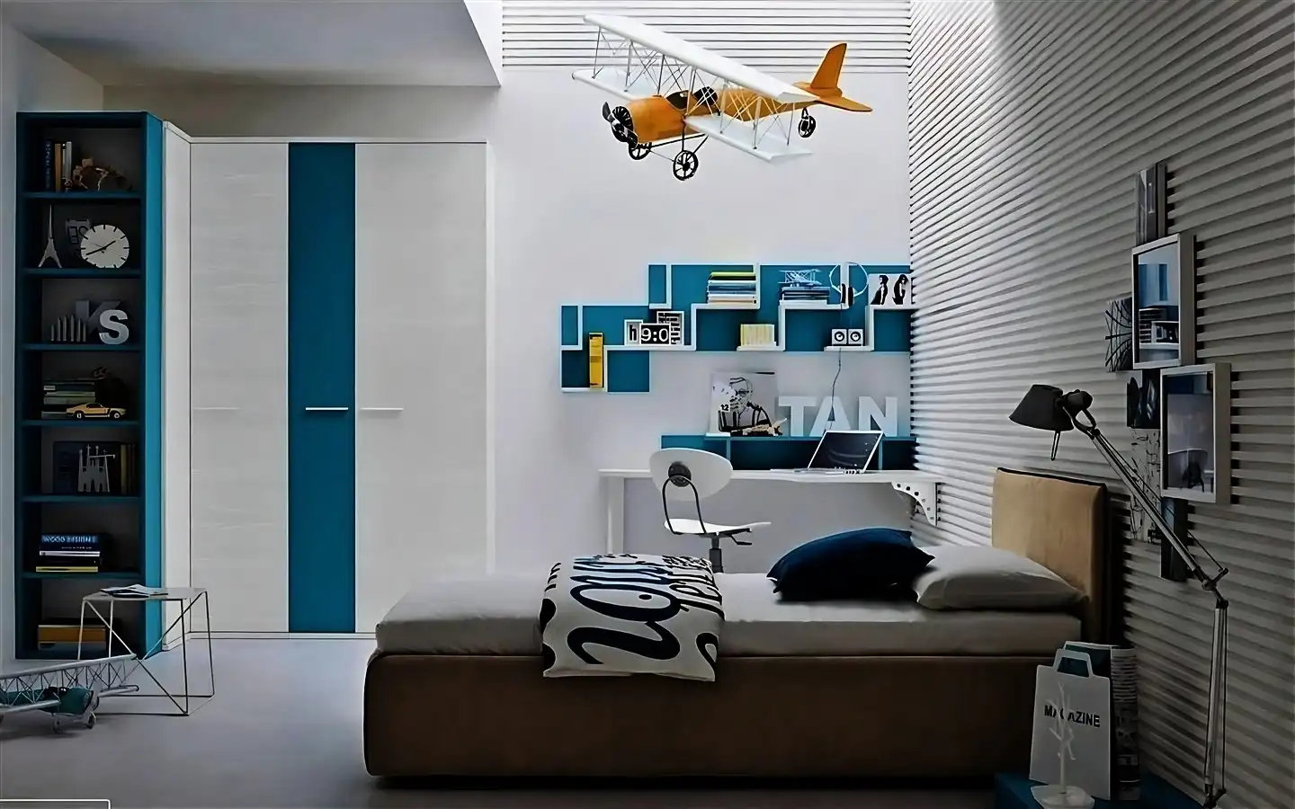 Modern teen boy bedroom design featuring teal and white furniture, a floating desk, wall-mounted geometric shelves, and a decorative hanging airplane