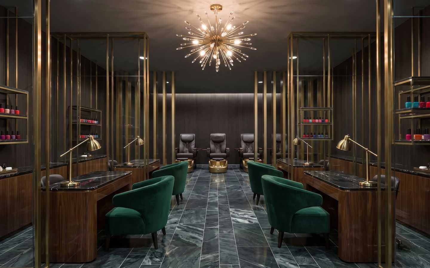 Dark luxury nail salon interior featuring green velvet chairs, black marble manicure tables, gold sputnik chandelier, and brass room dividers
