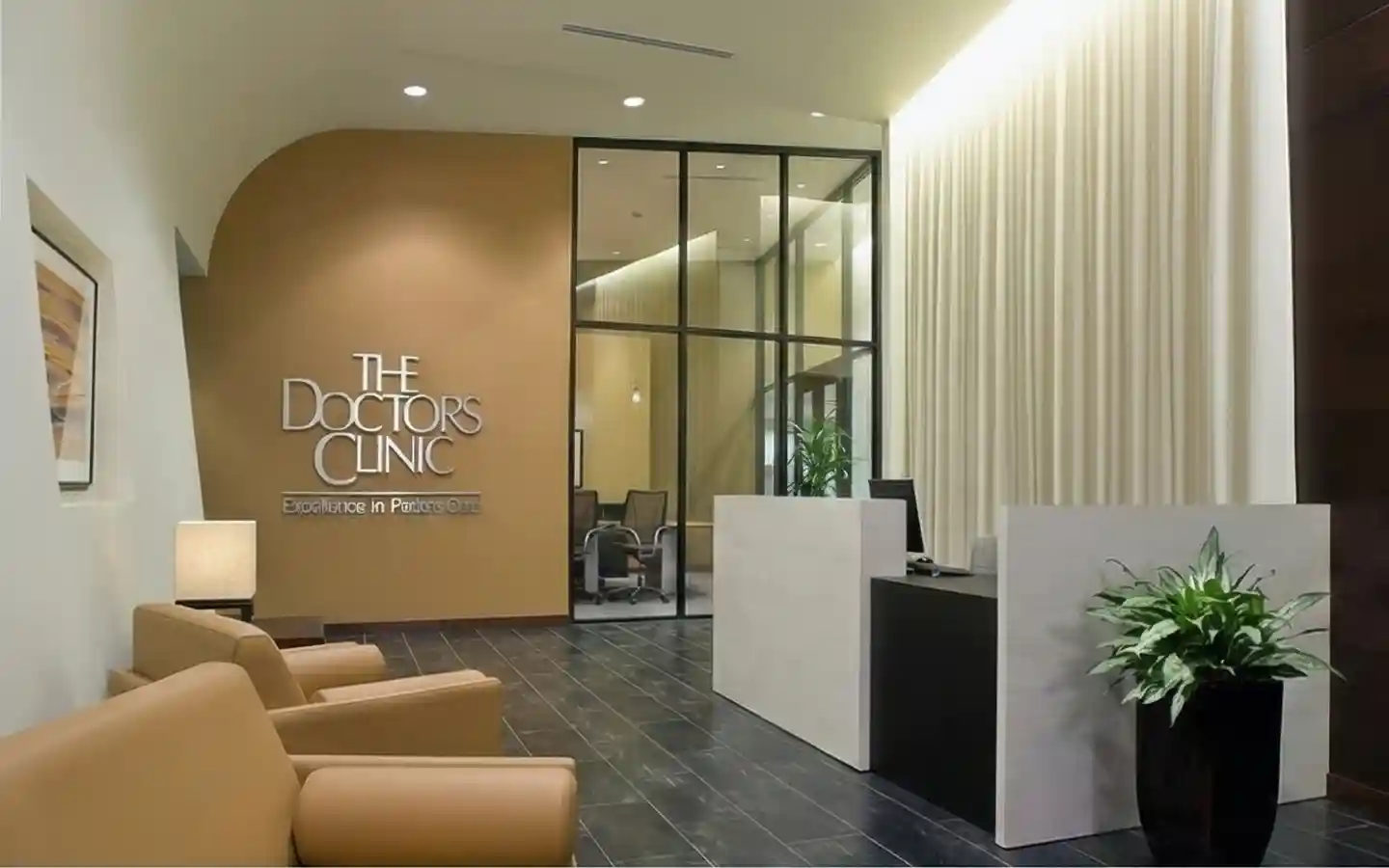 Upscale medical clinic lobby design featuring tan leather seating, a minimalist white reception desk, glass partitions, and a branded feature wall with accent lighting