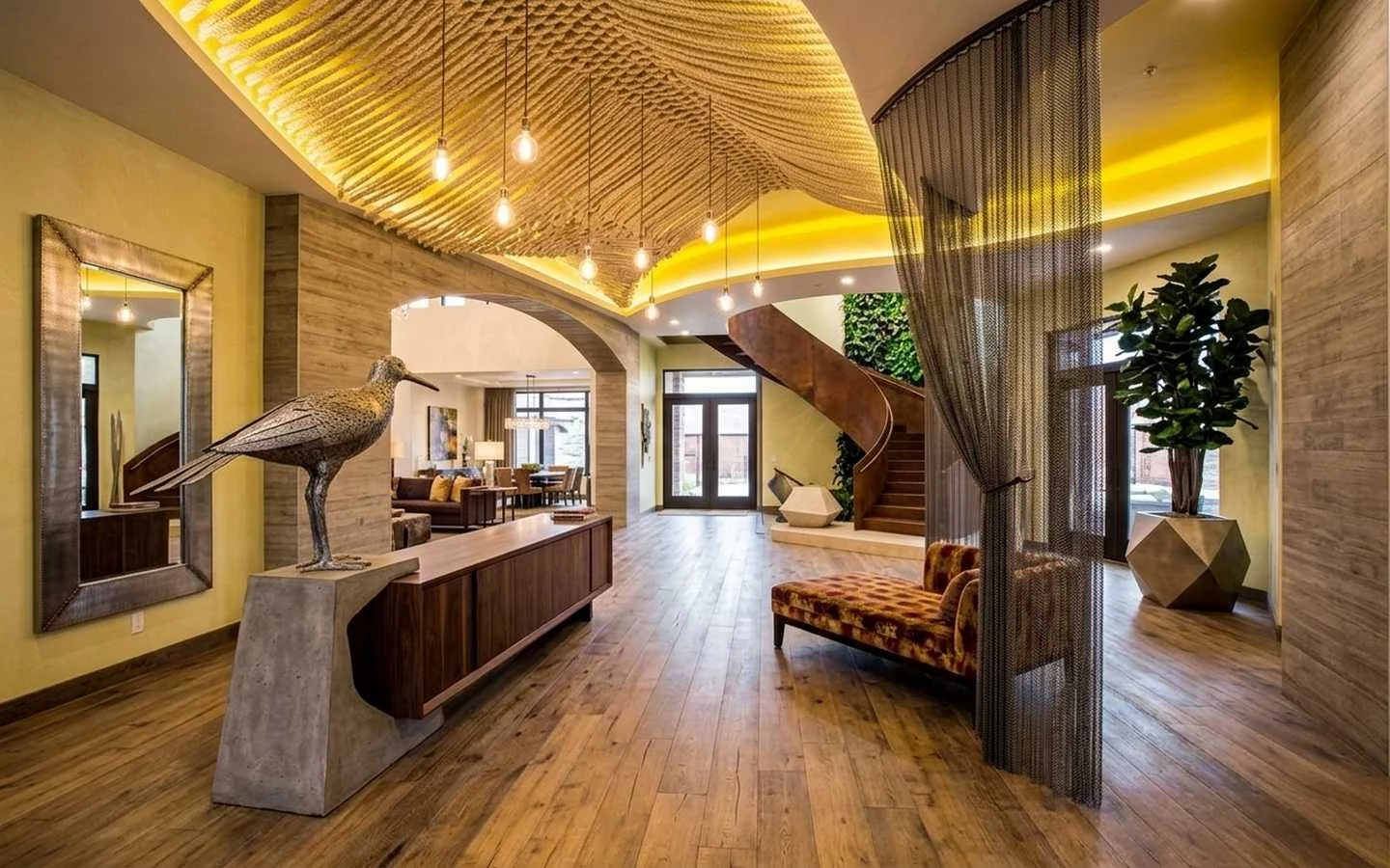 Rustic modern farmhouse entryway featuring a unique rope-textured ceiling, industrial mesh curtain, wood flooring, and a curved metal spiral staircase