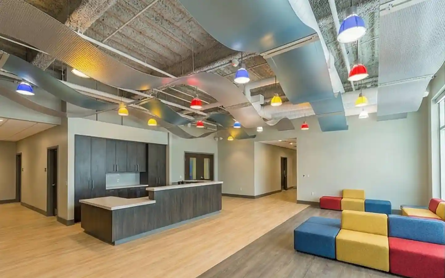 Modern school reception desk and lobby area with colorful modular seating and industrial wave ceiling design