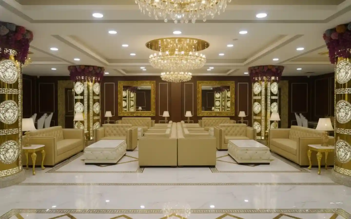VIP lounge area in a banquet hall featuring gold-trimmed pillars, tufted leather sofas, and crystal chandeliers